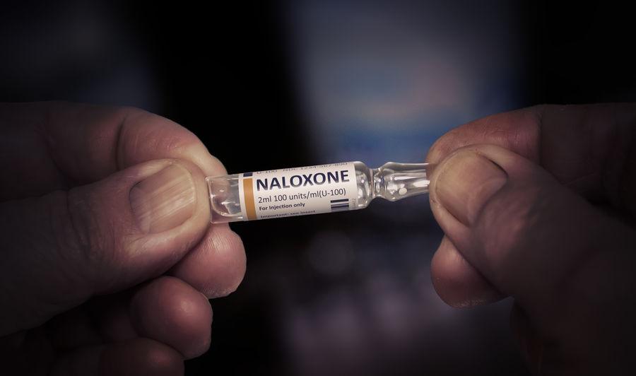 Hands holding a vial of Naloxone