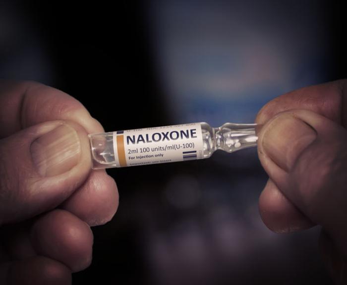Hands holding a vial of Naloxone