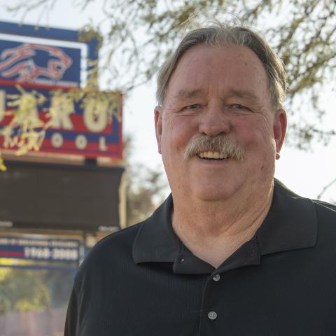 Clyde "Rocky" Brown in front of a Sahuaro High School sign