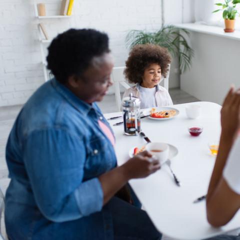 Two adults and a child eat at a table