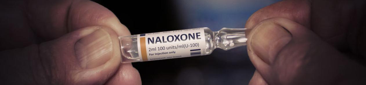 Hands holding a vial of Naloxone